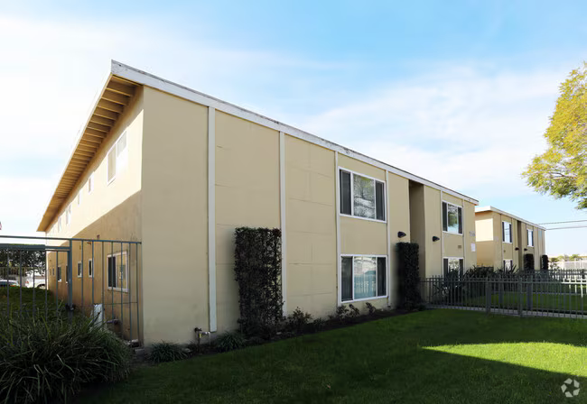 Low-rise multifamily property with perimeter fencing and green lawn
